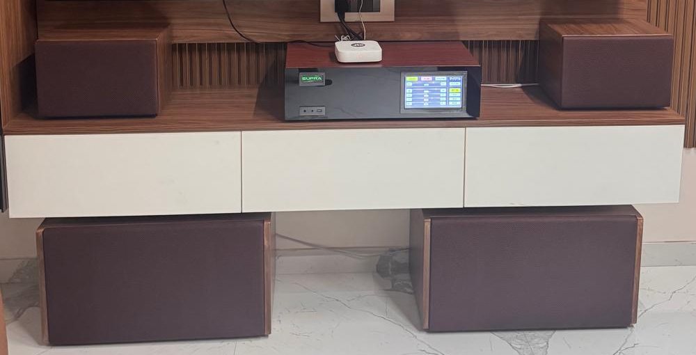 The amplifier installed in a TV unit between two speakers, with two subwoofers beneath
